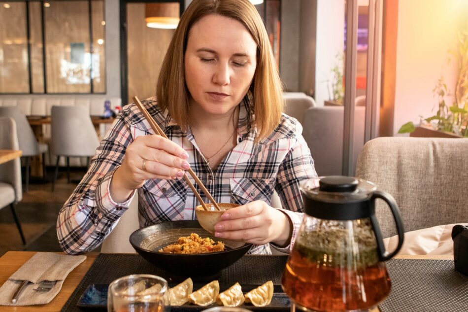 Girl eating Japanese food with chopsticks in restaurant