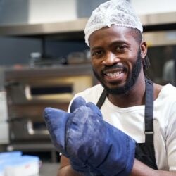 Smiling professional chef baking food in restaurant