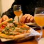 Woman eating pizza and drinking beer at the restaurant, food and drink